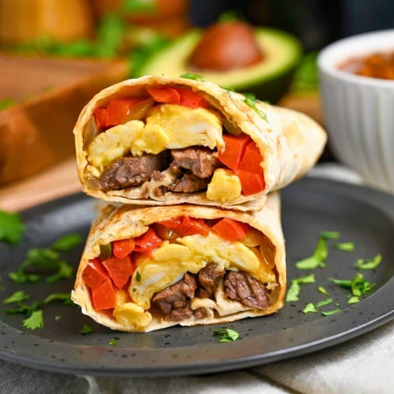 a sliced steak and egg burrito with cilantro sprinkled on top