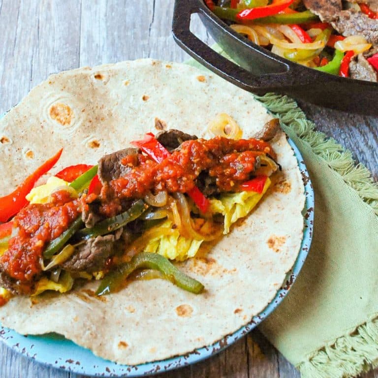 an open faced steak burrito on a plate with salsa