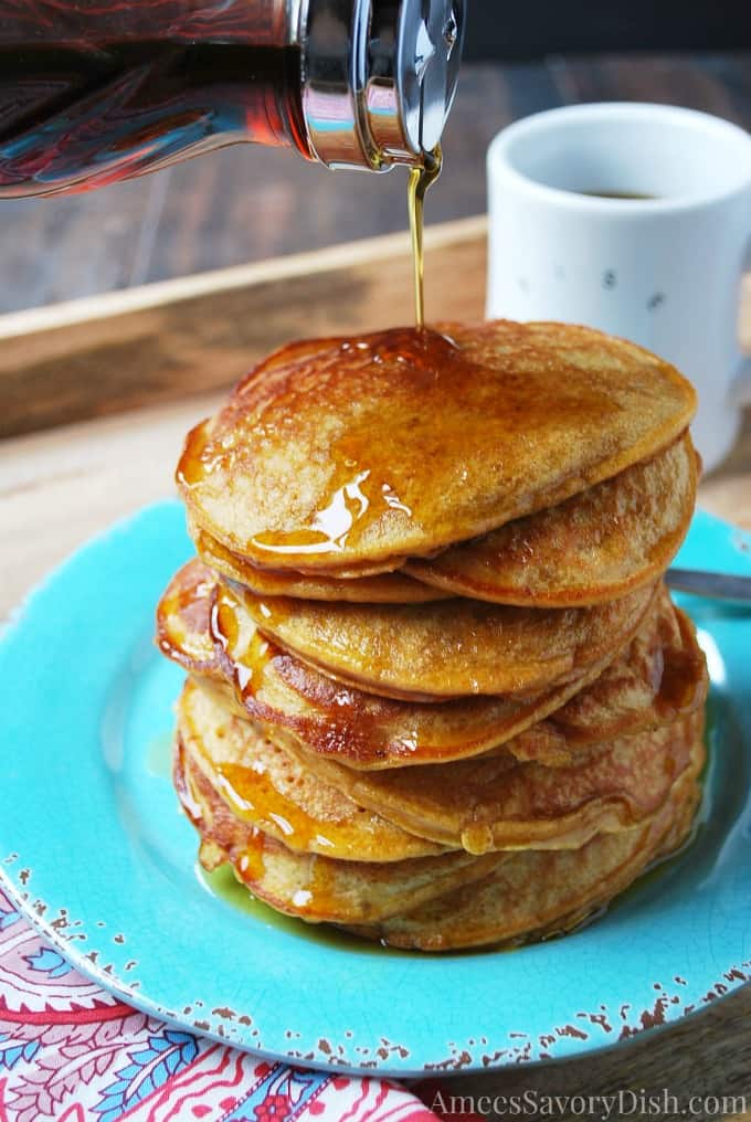 pouring syrup on a stack of sweet potato pancakes
