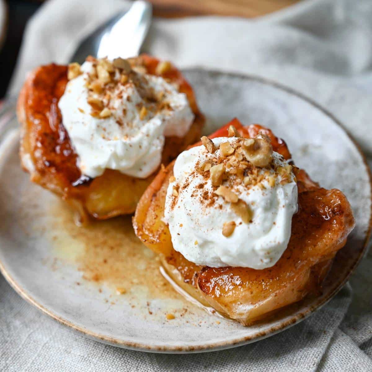 two cooked apple halves on a plate with toppings