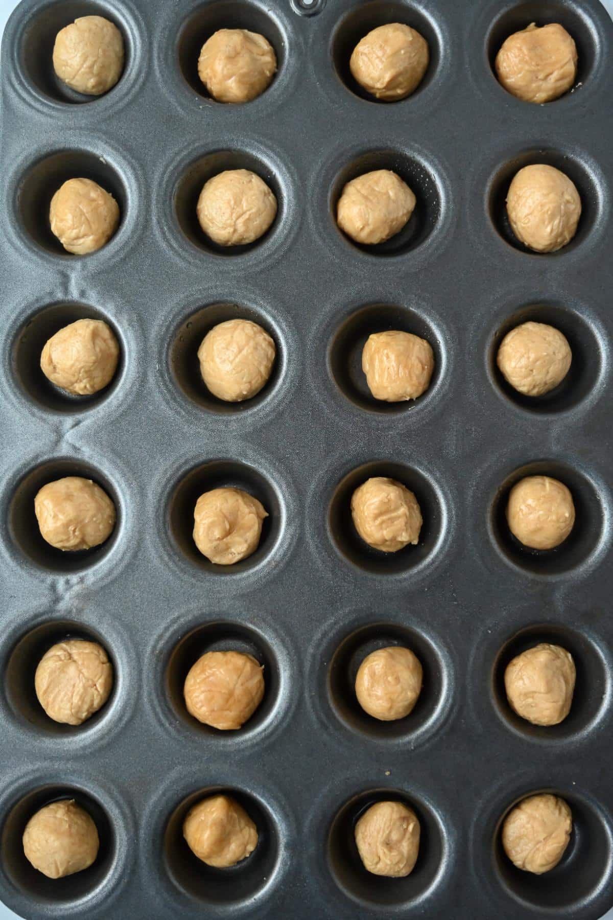 cookie dough balls in a mini muffin pan