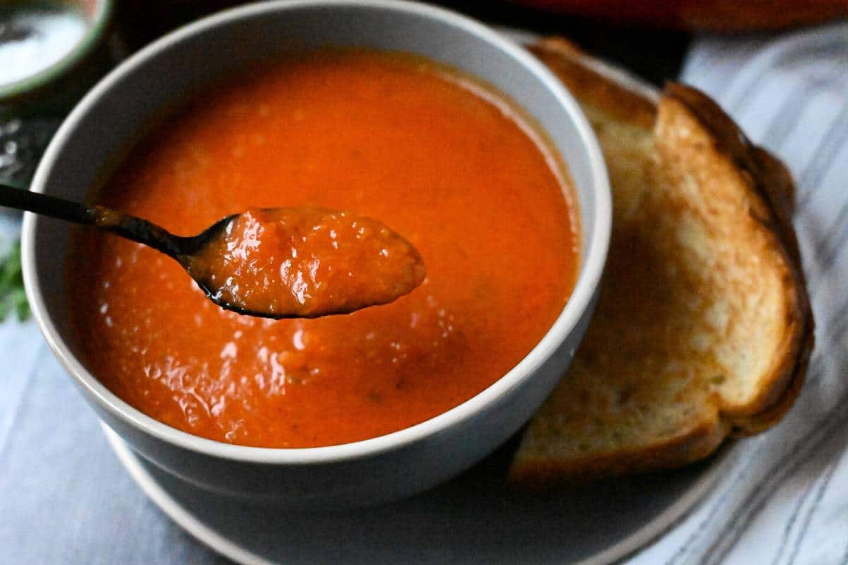 spoonful of tomato bisque over a bowl 