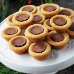 peanut butter cookie cups stuffed with a mini Reece's peanut butter cup stacked on a white platter