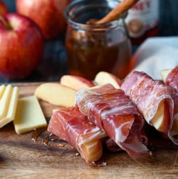 apple and cheese wrapped in prosciutto on a cutting board