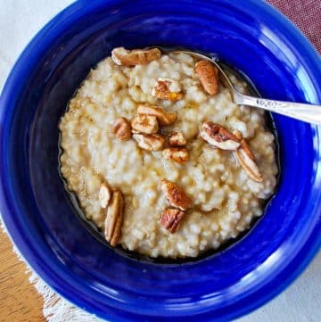 overhead photo of a bowl of steel cut oats with pecans and maple syrup and a spoon