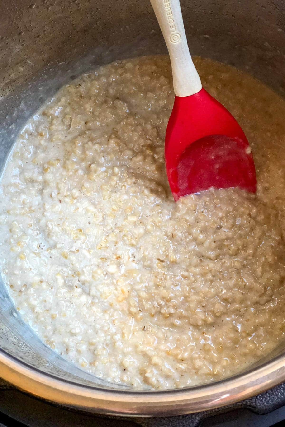steel cut oats being stirred with a spatula in an instant pot