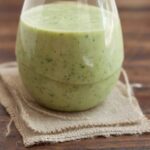 green monster smoothie in a glass with a napkin underneath