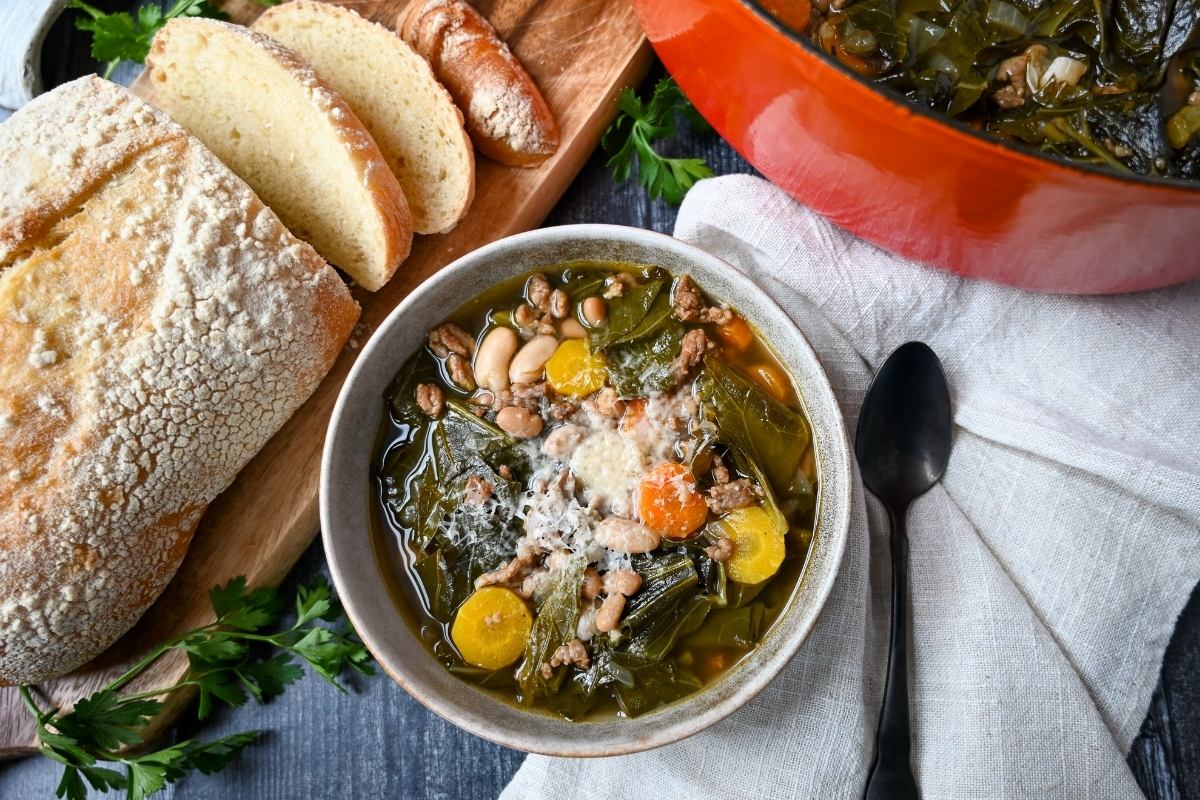 a bowl of collard soup topped with parmesan cheese with a spoon and napkin