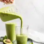 pouring a green smoothie into a glass