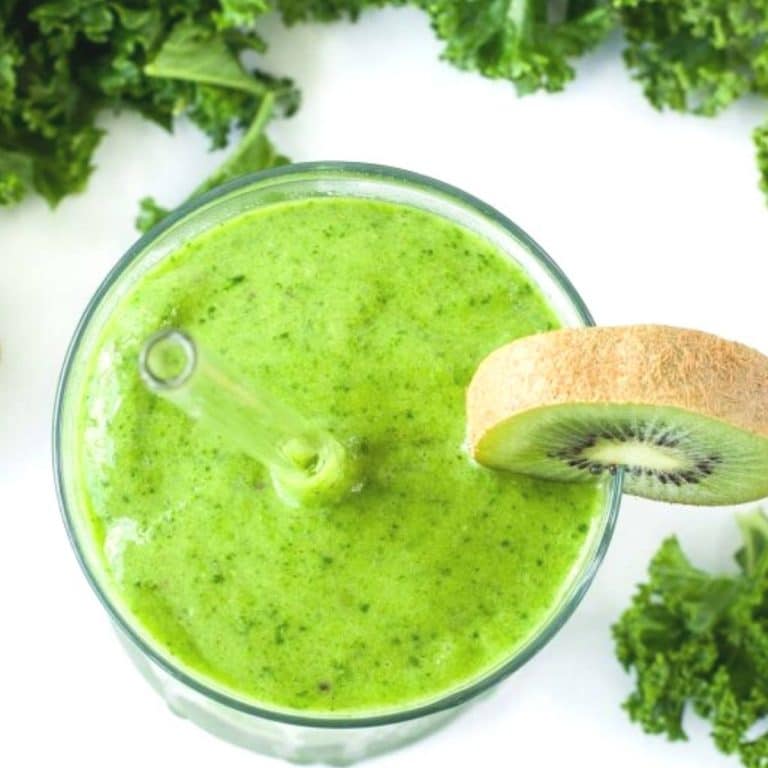 overhead photo of a green smoothie with a slice of kiwi on the rim