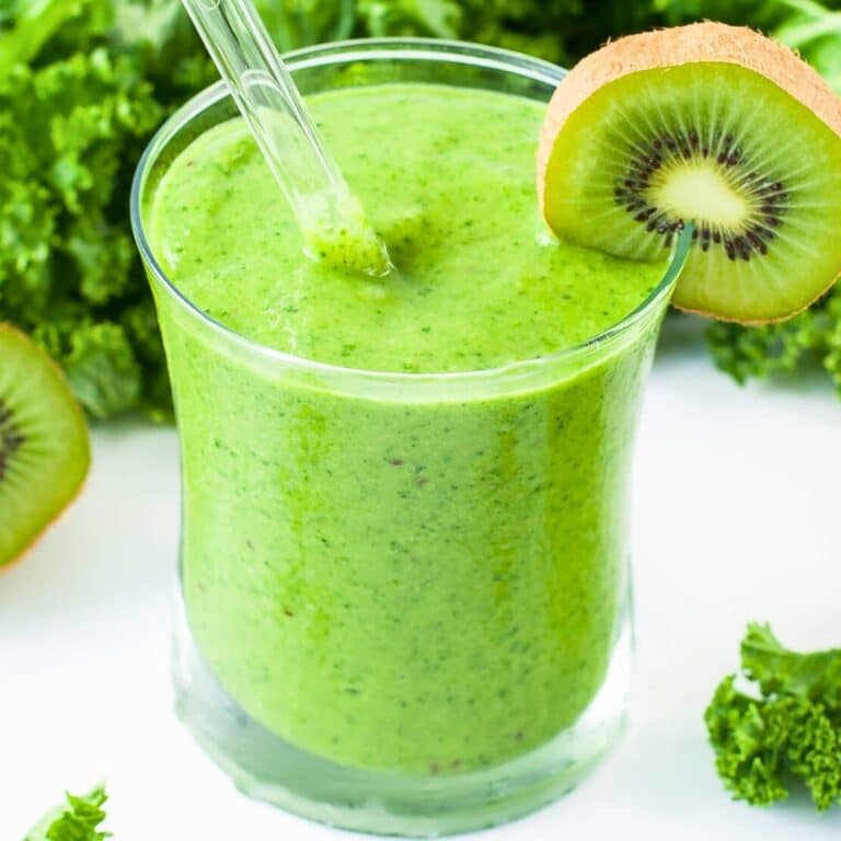 a green smoothie in a glass with a slice of kiwi