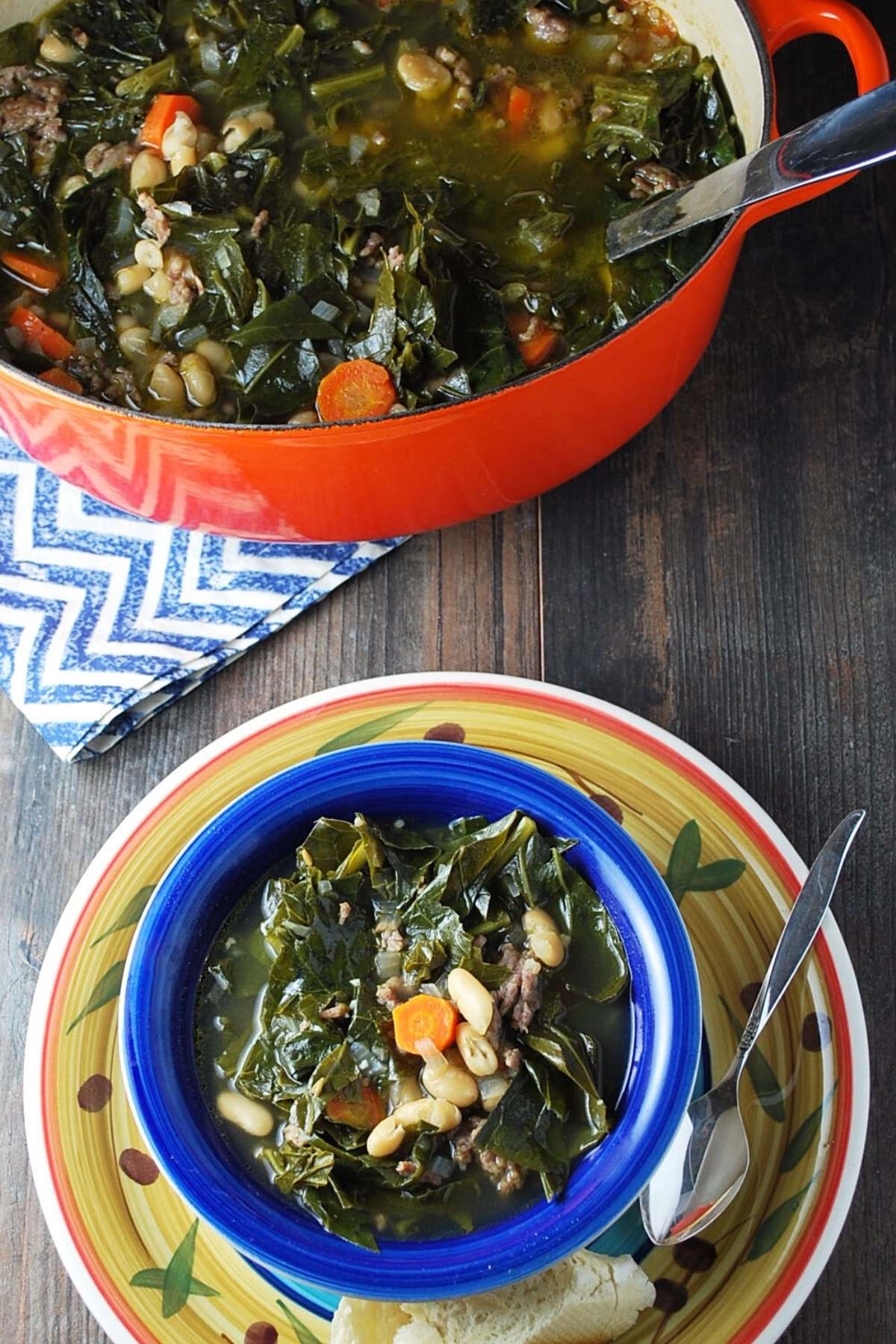 overhead photo of a bowl of sausage bean soup with collards and a pot of soup with a spoon