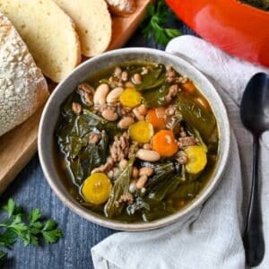 close up of a bowl of collard soup with beans and sausage