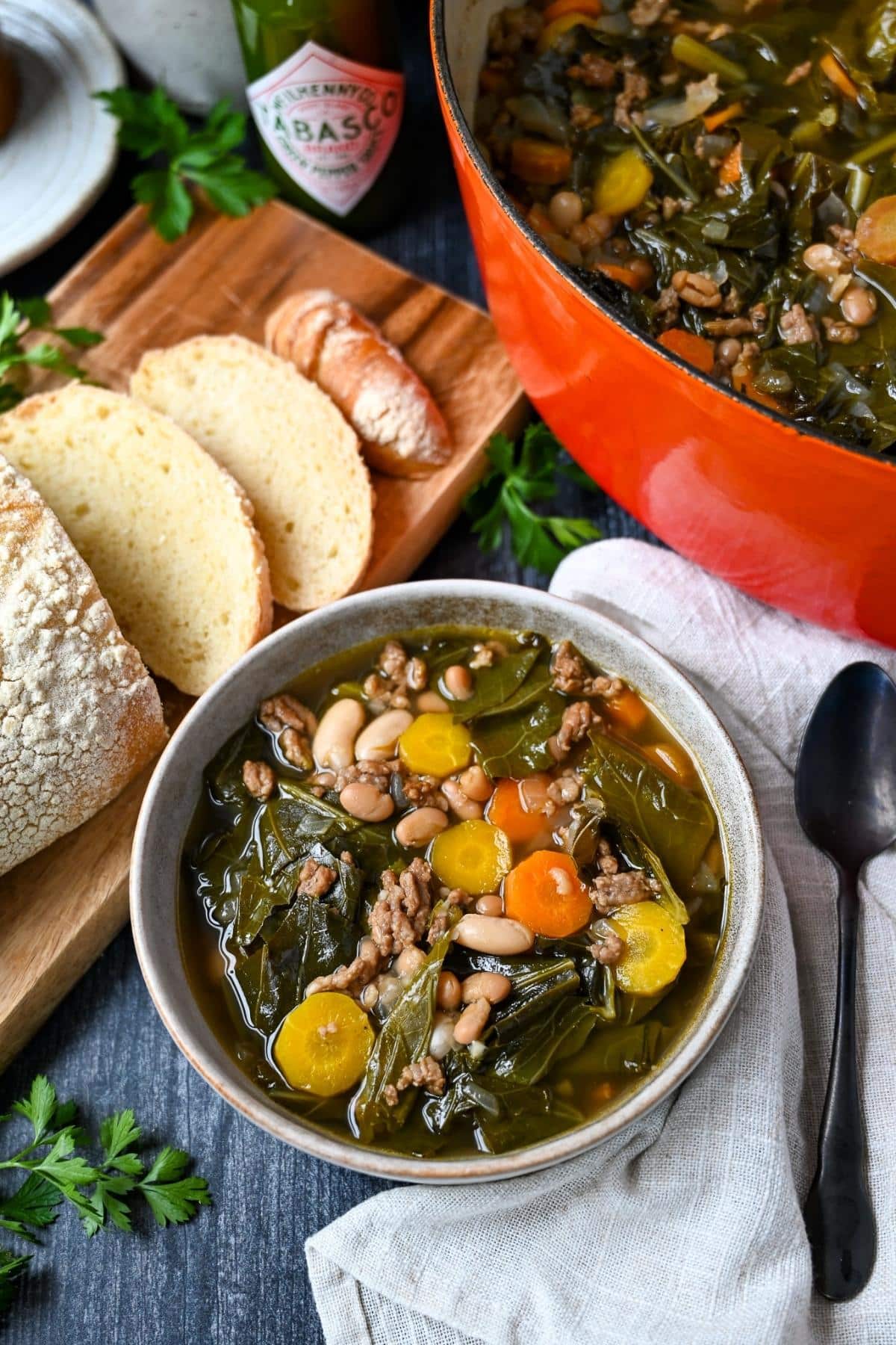 a bowl of collard soup with slice bread and a pot of soup