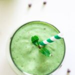 a green smoothie with chocolate chips and a sprig of mint on top