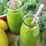 two green smoothies in jars with a striped straw