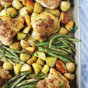 roasted chicken with potatoes and green beans in a sheet pan topped with fresh parsley