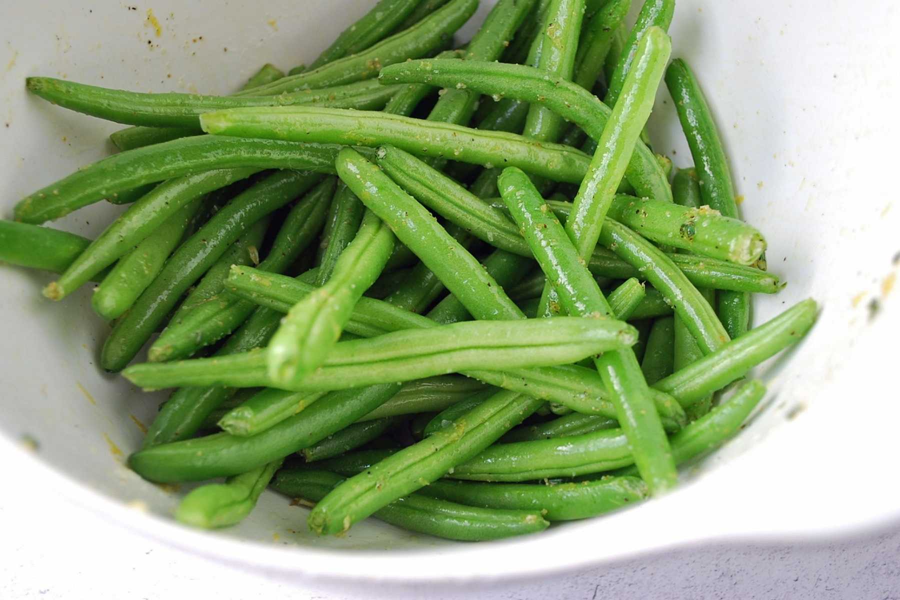 fresh green beans in a bowl tossed with marinade