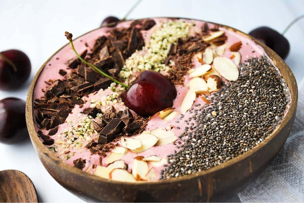 side view of a cherry smoothie bowl with a fresh red cherry on top