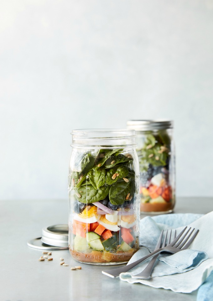 Mason jars with meal prepped salads, forks, and napkin