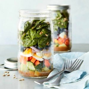 two superfood salads in jars with forks and a napkin