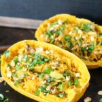 two asian stuffed spaghetti squash halves on a baking pan