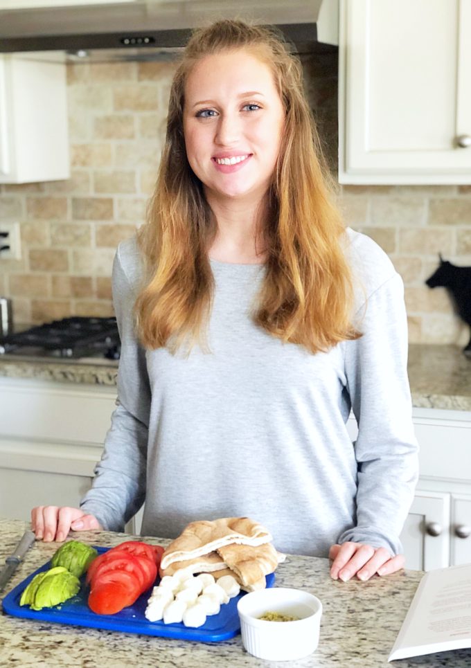 Girl standing behind the kitchen counter with a platter of food