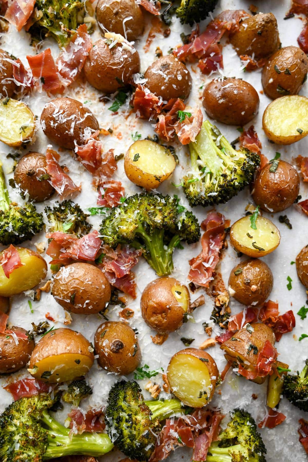 overhead photo of a one-pan roasted broccoli and potatoes with prosciutto and fresh parmesan grated on top
