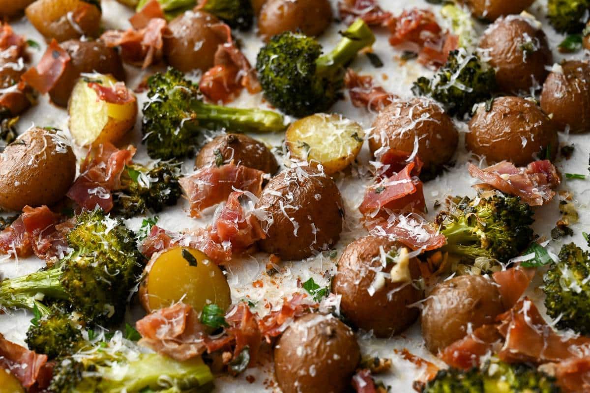 close up of red potatoes and broccoli topped with parmesan cheese with crispy roasted prosciutto ham