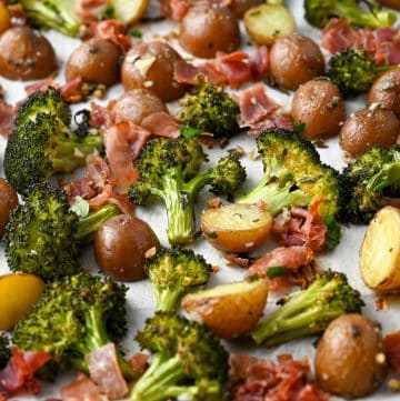 close up of roasted broccoli and potatoes on a sheet pan with crispy prosciutto
