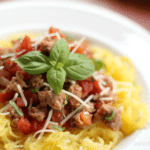 a bowl of spaghetti squash with Italian sausage sauce on top