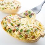 carbonara spaghetti squash boats with a fork holding up a bite