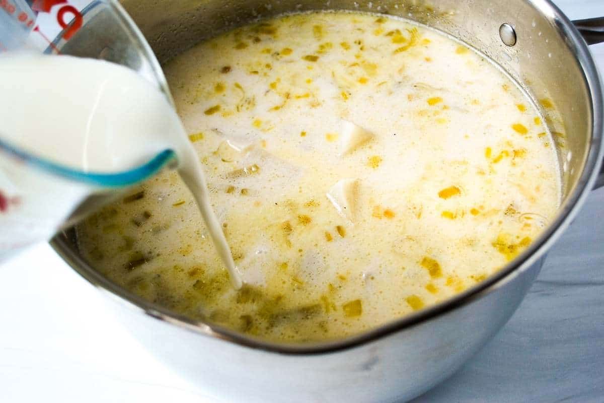 Pouring milk and cornstarch mixture into potato leek soup in a pot 