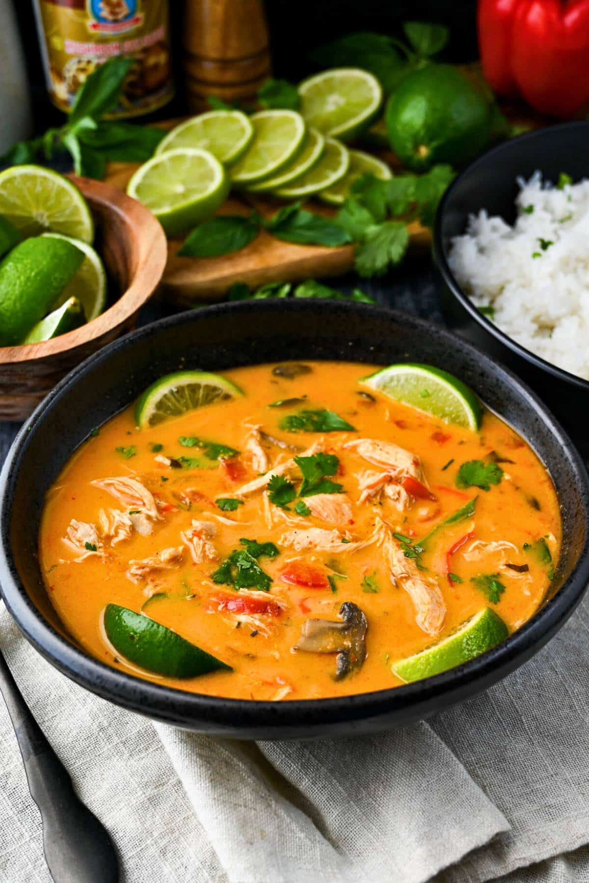 a bowl of thai curry chicken soup with limes and herbs
