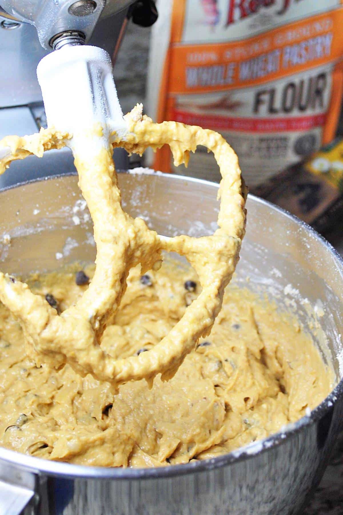 pumpkin banana muffin batter in a stand mixer with bag of flour behind it