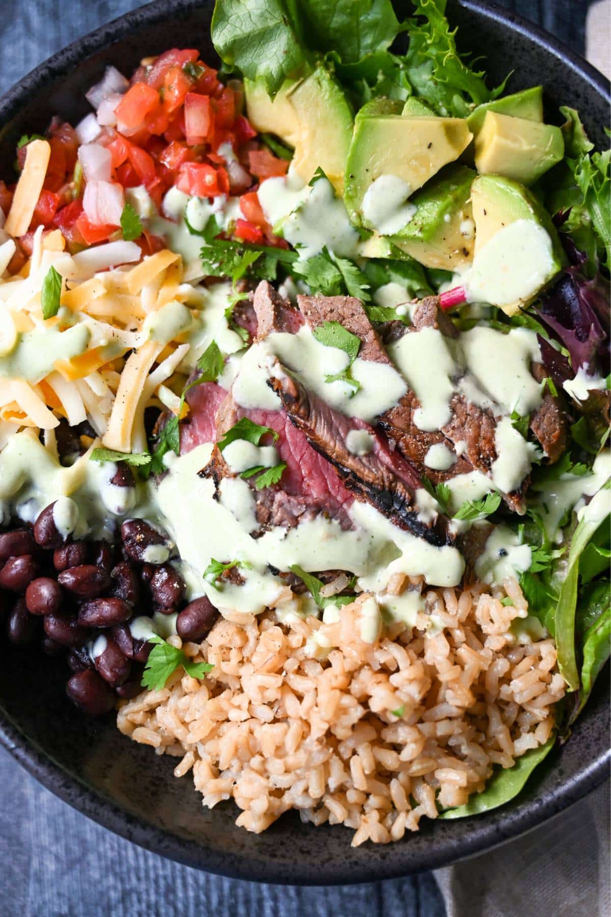 steak rice bowl with creamy verde dressing drizzled on top