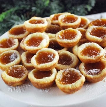 apricot tarts on a white platter with greenery in the background