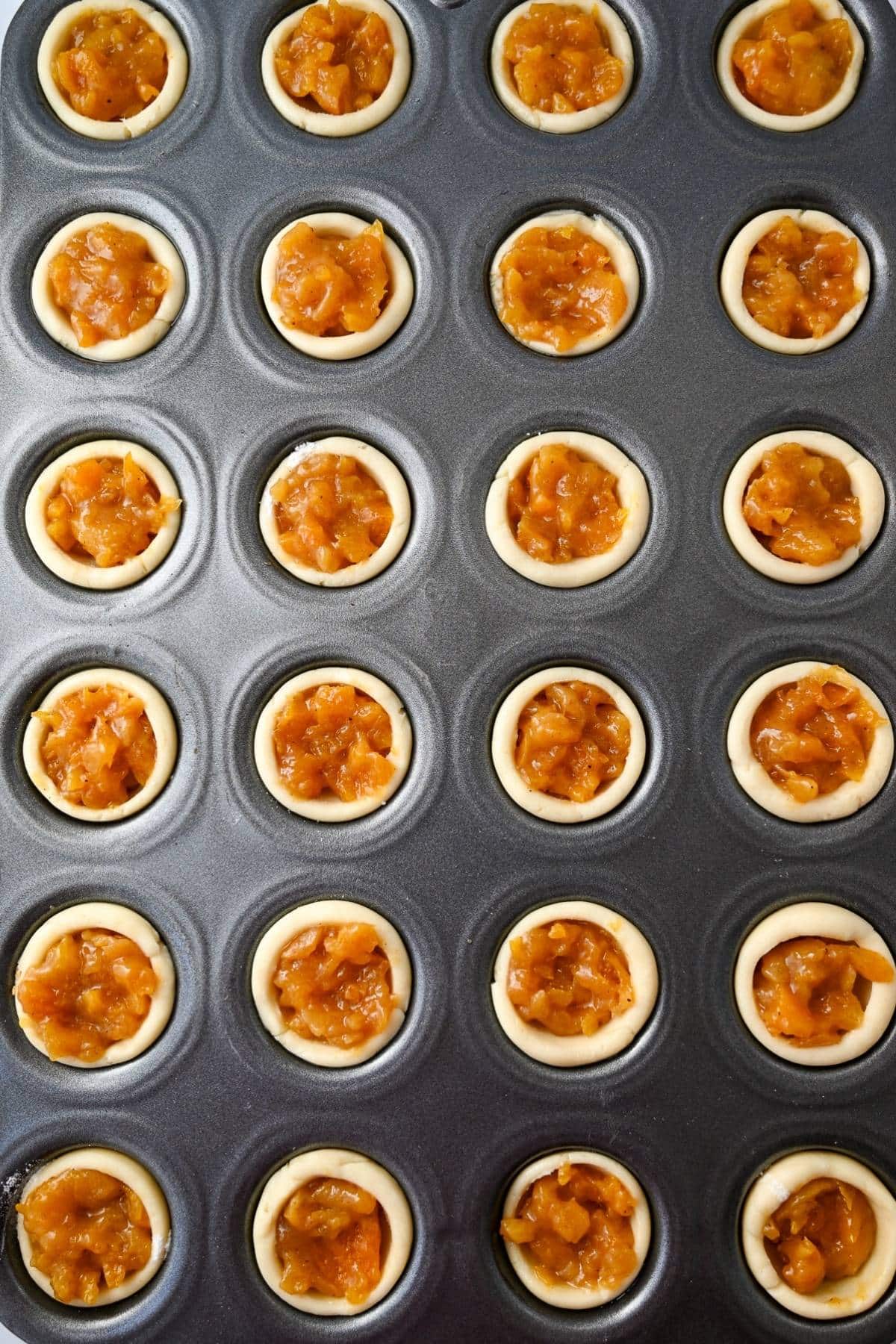 tart shells filled with a homemade apricot filling in a mini muffin pan