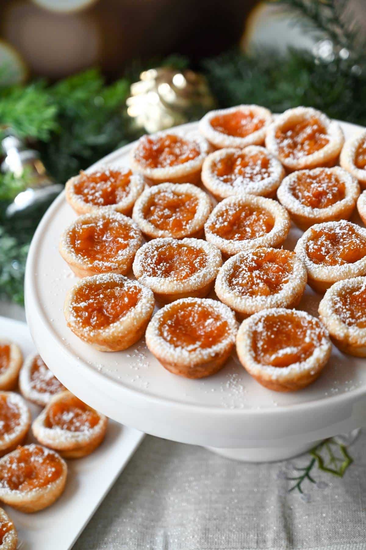 homemade apricot tarts on a white holiday platter dusted with powdered sugar