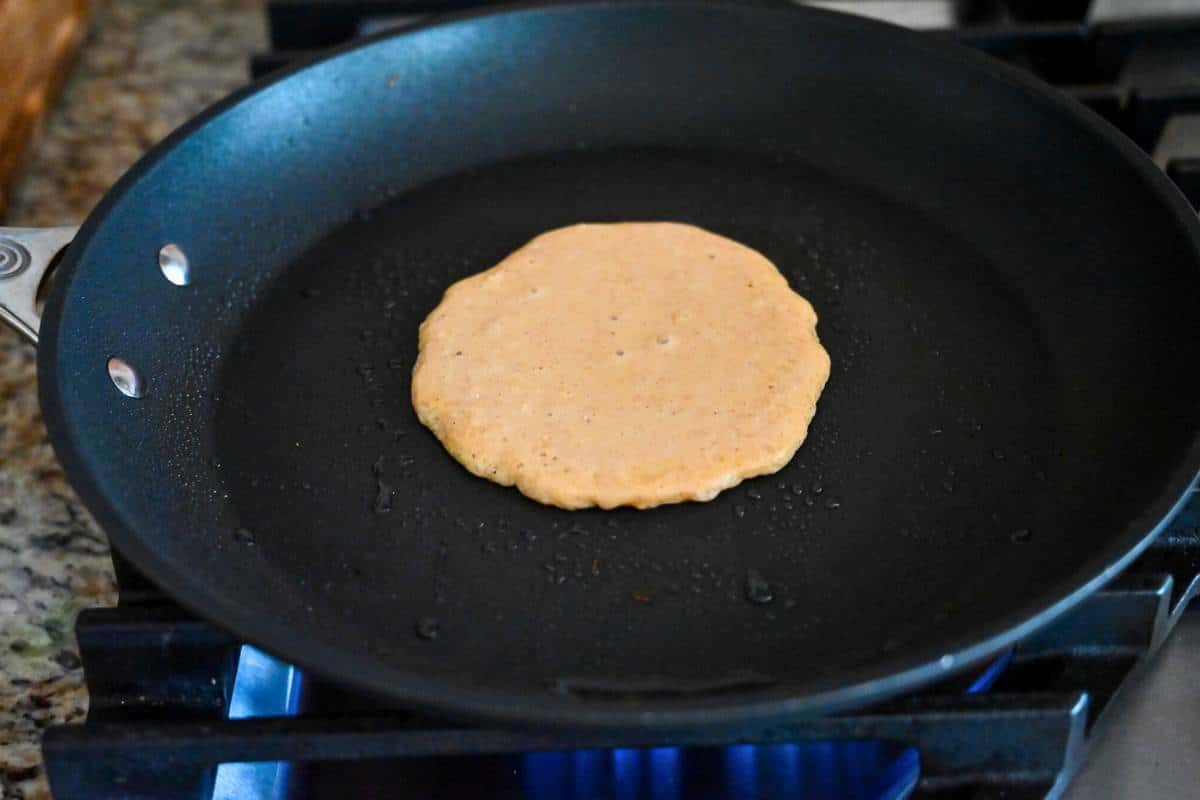 pancake batter in a skillet ready to flip
