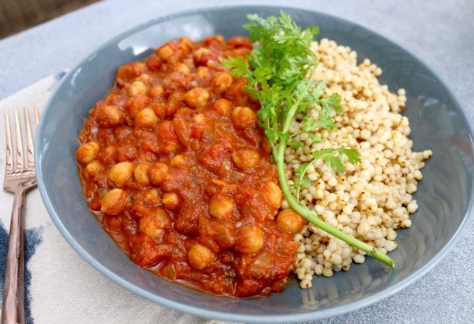 Chickpea curry in a bowl with couscous and fresh parsley