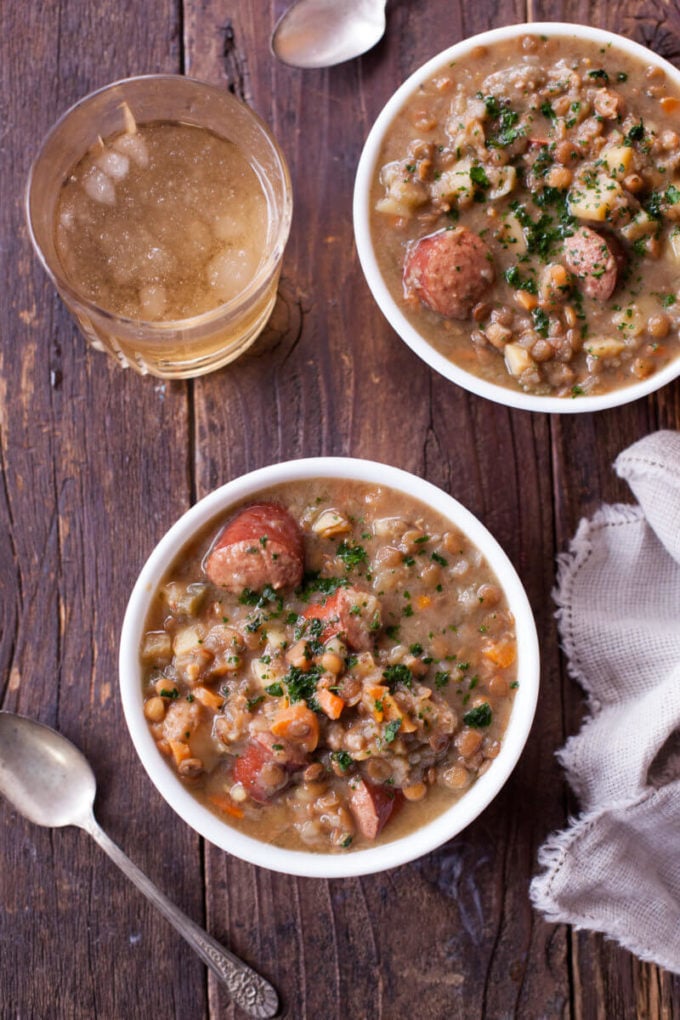 Two bowls of lentil sausage soup with glass of tea