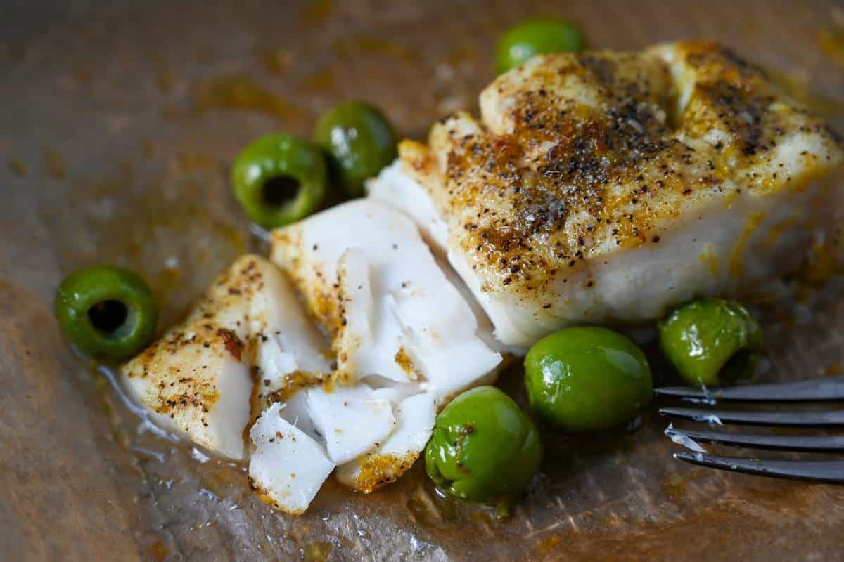 a flaked piece of cooked halibut with olives