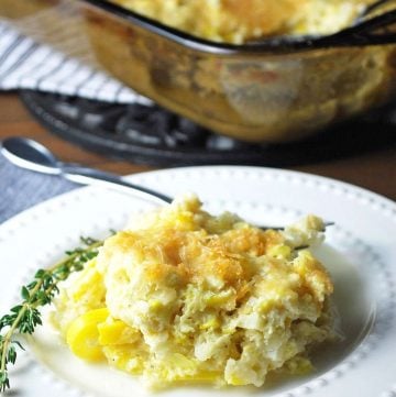 squash casserole on a plate with a sprig of thyme and a fork