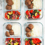 Glass meal prep containers with roasted vegetables, rice, and meatballs