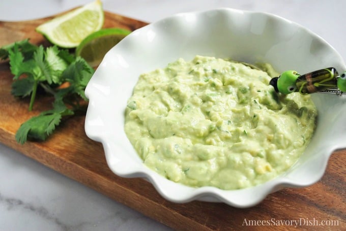 avocado dip in a white bowl on a cutting board