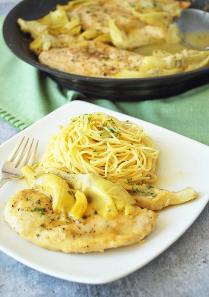 Boneless chicken breast with lemon and artichokes on a plate with pasta