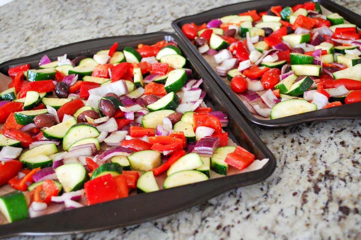 raw vegetables on parchment lined baking sheets