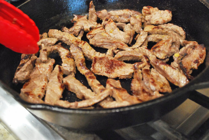 Cooked steak strips in a cast iron skillet