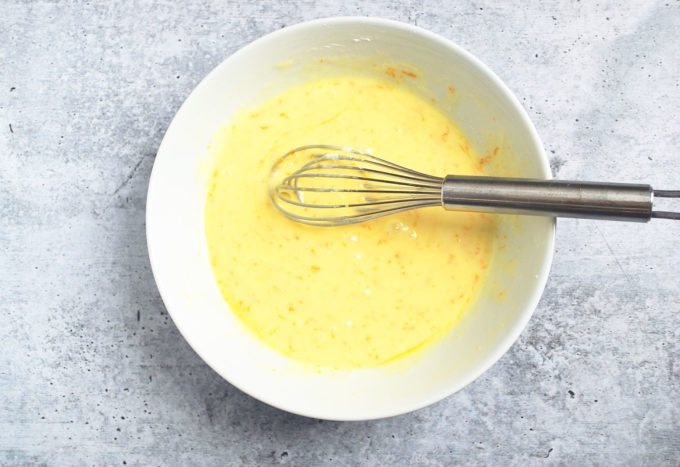 Orange glaze in a white bowl with a whisk